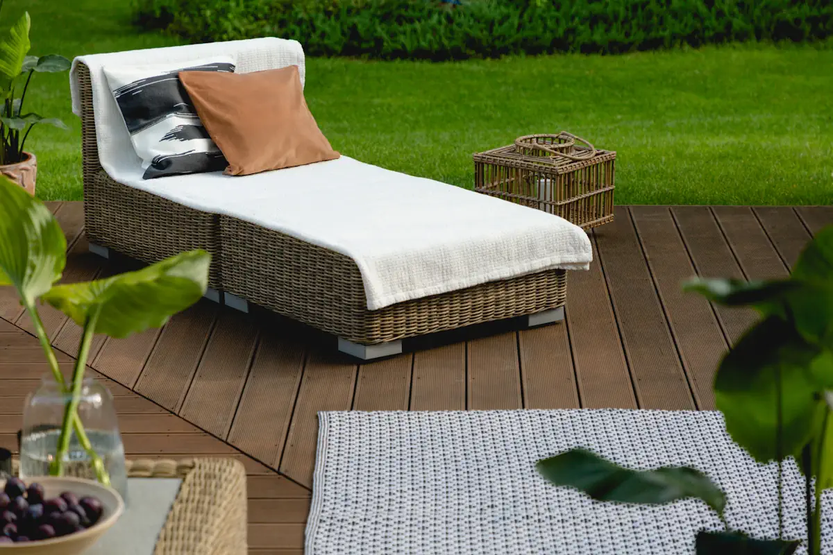 Une terrasse en bois où est posé un transat en rotin