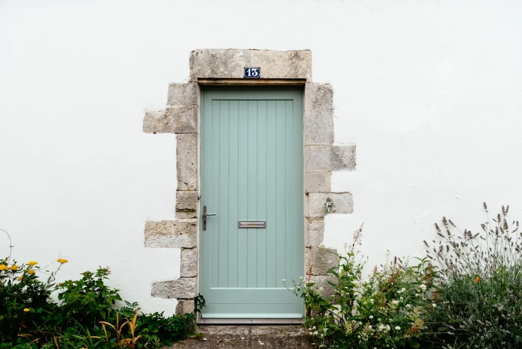 Une porte ancienne bleu claire avec des linteaux en pierre