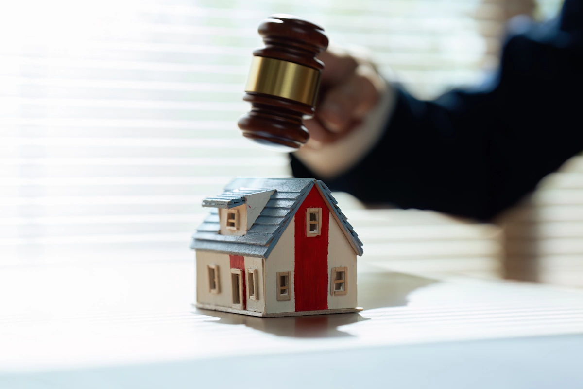 Un homme qui tient un marteau sur une maquette de maison 