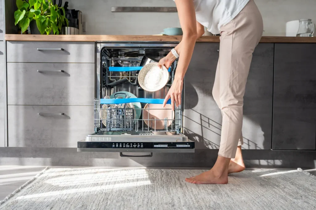 Une femme qui range des vaisselles dans un lave-vaisselle
