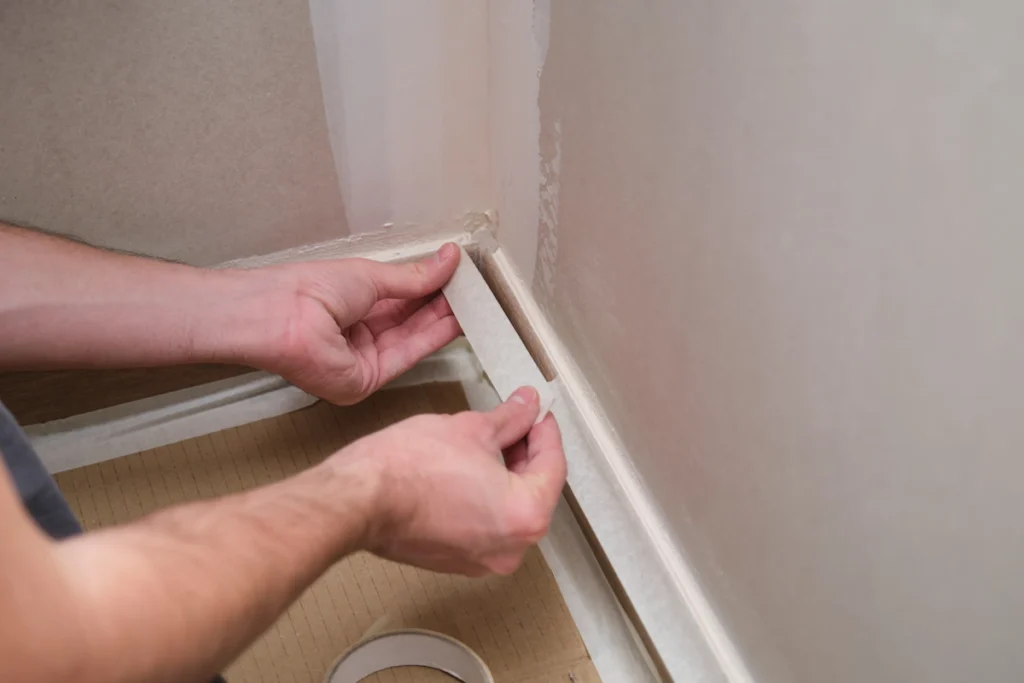 Une personne qui colle un morceau de plinthe sur le mur
