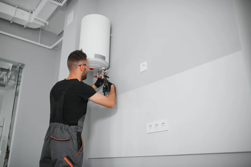 Un homme qui installe un chauffe-eau contre un mur