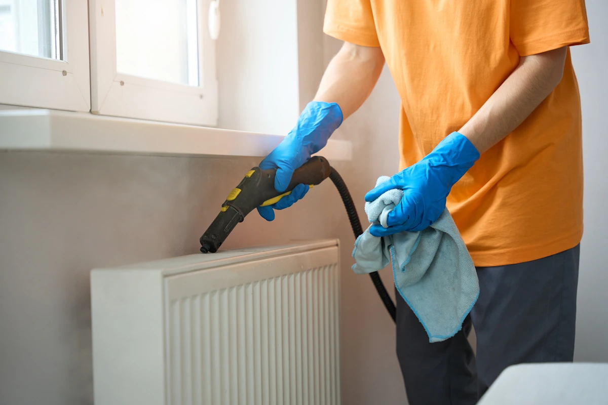 Une personne qui nettoie un radiateur avec un appareil