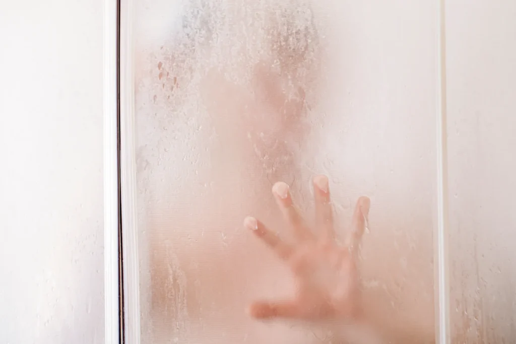 Une main qui apparaît ç travers la condensation salle de bain