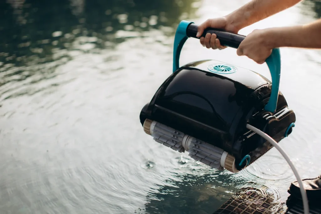 Une personne qui entretien un robot de piscine