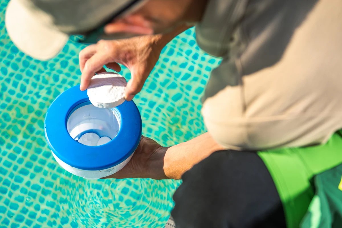 Une personne qui place des floculant en galets dans une piscine