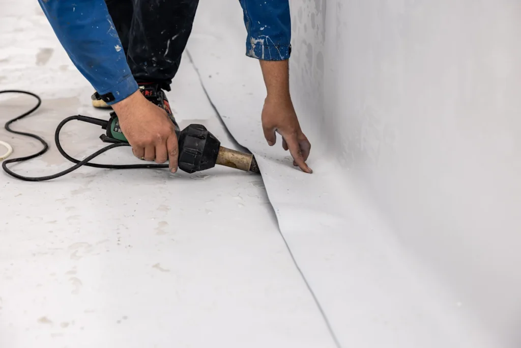 Une personne qui répare un liner piscine décolle