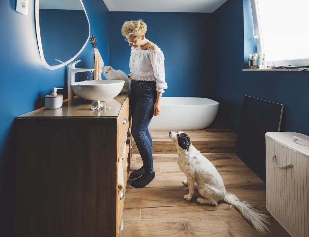 Une femme et son chien qui regarde les meubles de la salle de bain